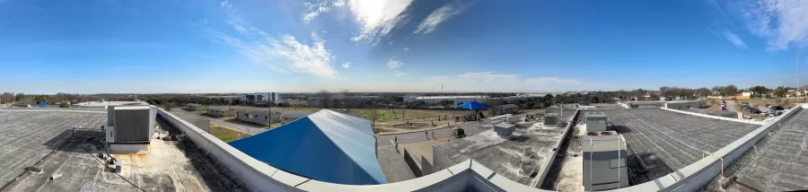 View looking out from the roof of the HART Elementary School, showing a playground, school buildings, and the Northern skyline of Austin Texas